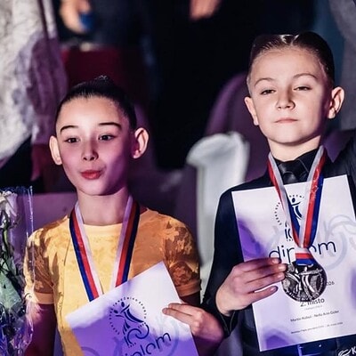 Dívky z Kometka Family na soutěži MČR v latině, drží medaile a diplomy, oslavují úspěch.